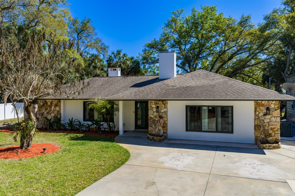 Front exterior of renovated ranch home with stone accents and circular driveway, Vero Beach FL