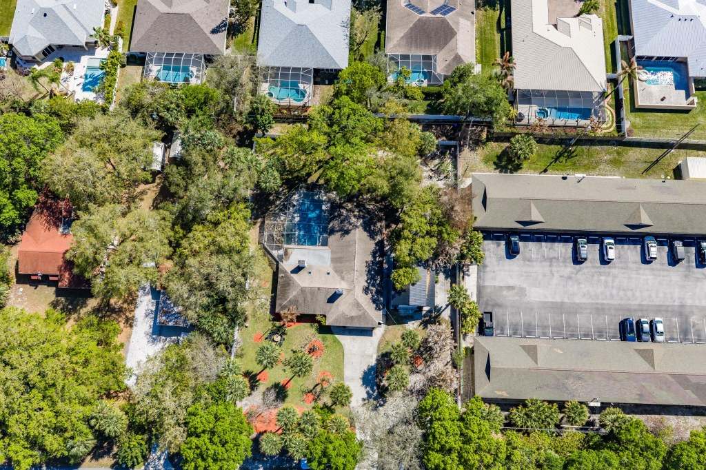 Aerial drone photo of Vero Beach pool home showing screened pool enclosure and wooded lot