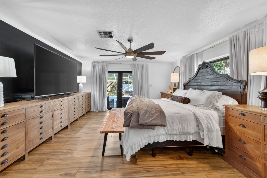 Primary bedroom with farmhouse dressers and French doors to the lanai, renovated Vero Beach home