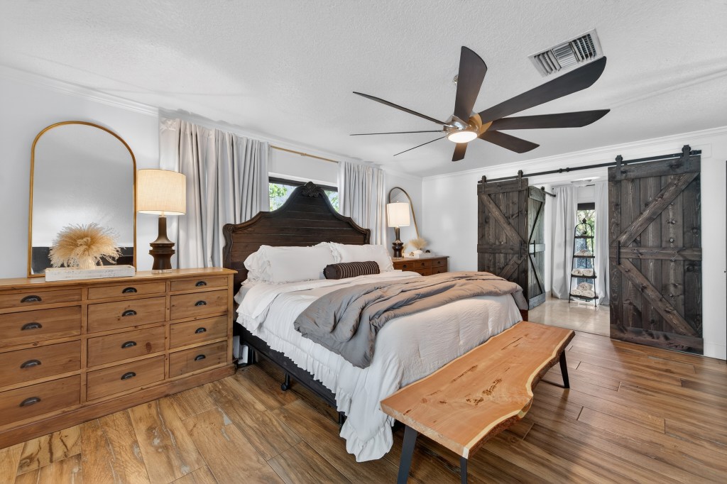 Primary bedroom with carved wood headboard and barn doors to the ensuite, Vero Beach home photography