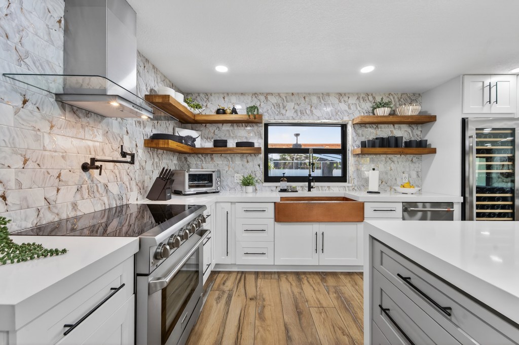 White shaker kitchen with copper farmhouse sink and marble backsplash, Vero Beach listing photography